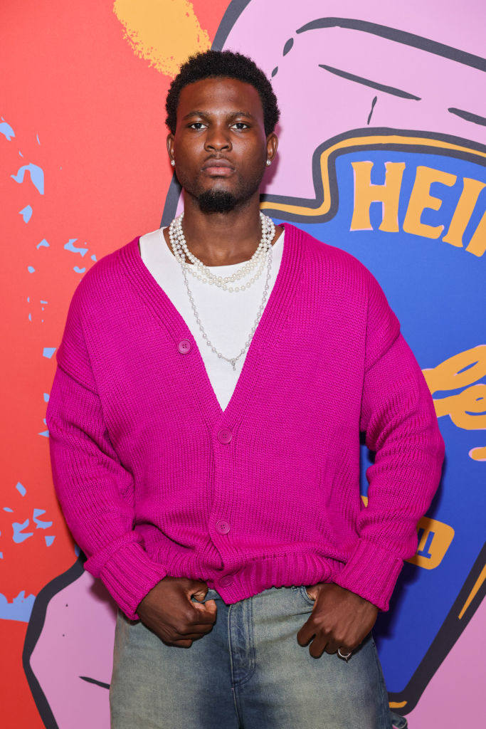 Martin in vibrant sweater and jeans with hands in pockets against a graphic backdrop