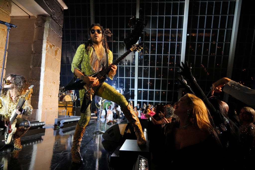 Lenny in patterned attire playing electric guitar onstage with audience in foreground