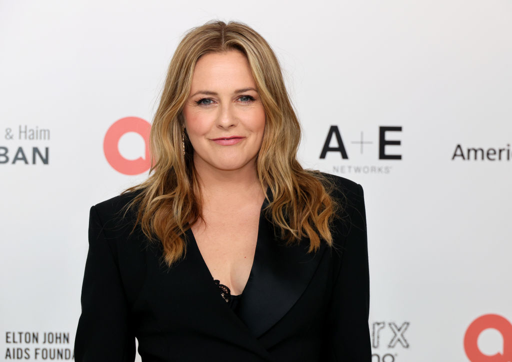 Alicia Silverstone wearing a black blazer and top, posing at an event