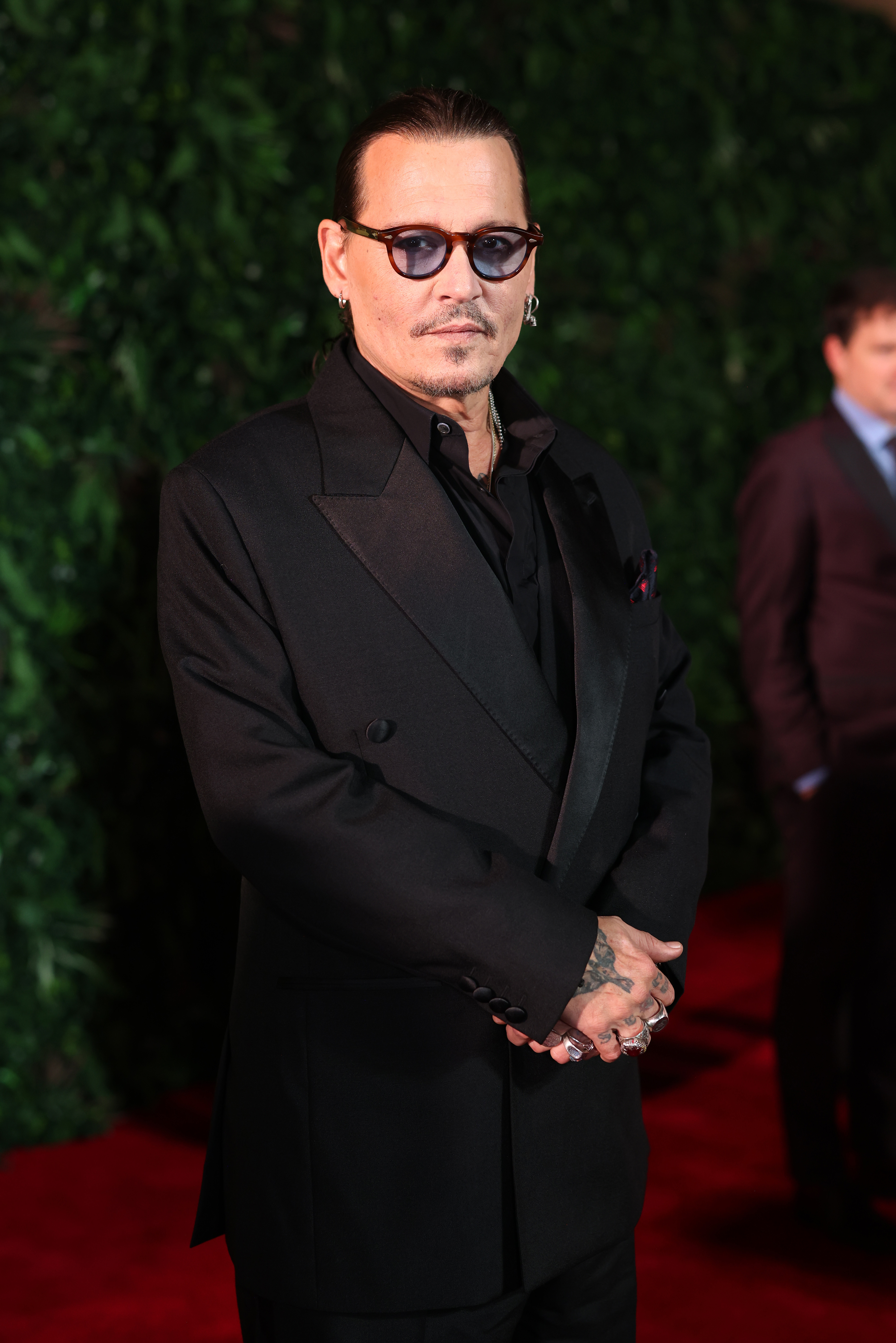 Johnny Depp in a black suit and sunglasses posing at an event