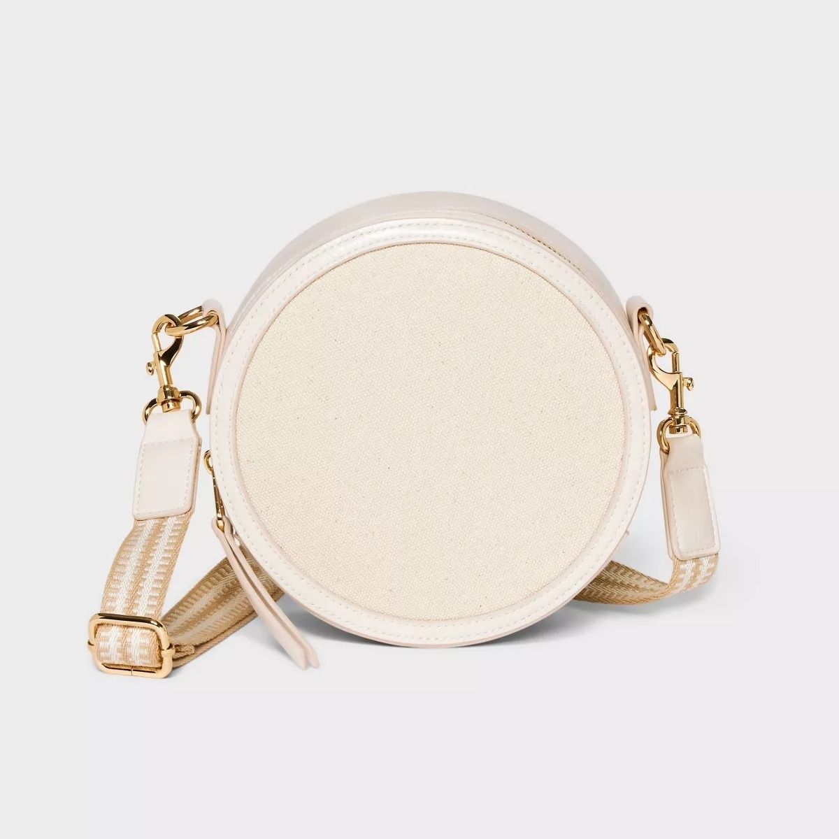Round white fabric crossbody bag with a gold-toned strap buckle