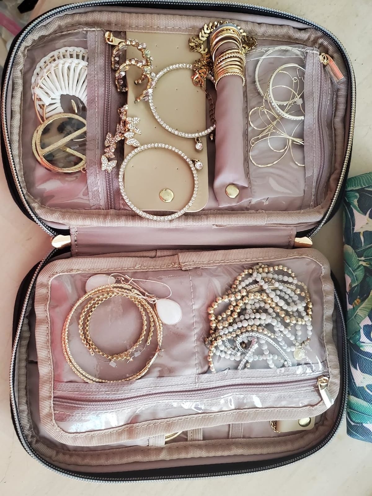 Reviewer&#x27;s photo of the open jewelry organizer with assorted necklaces and earrings, suitable for travel