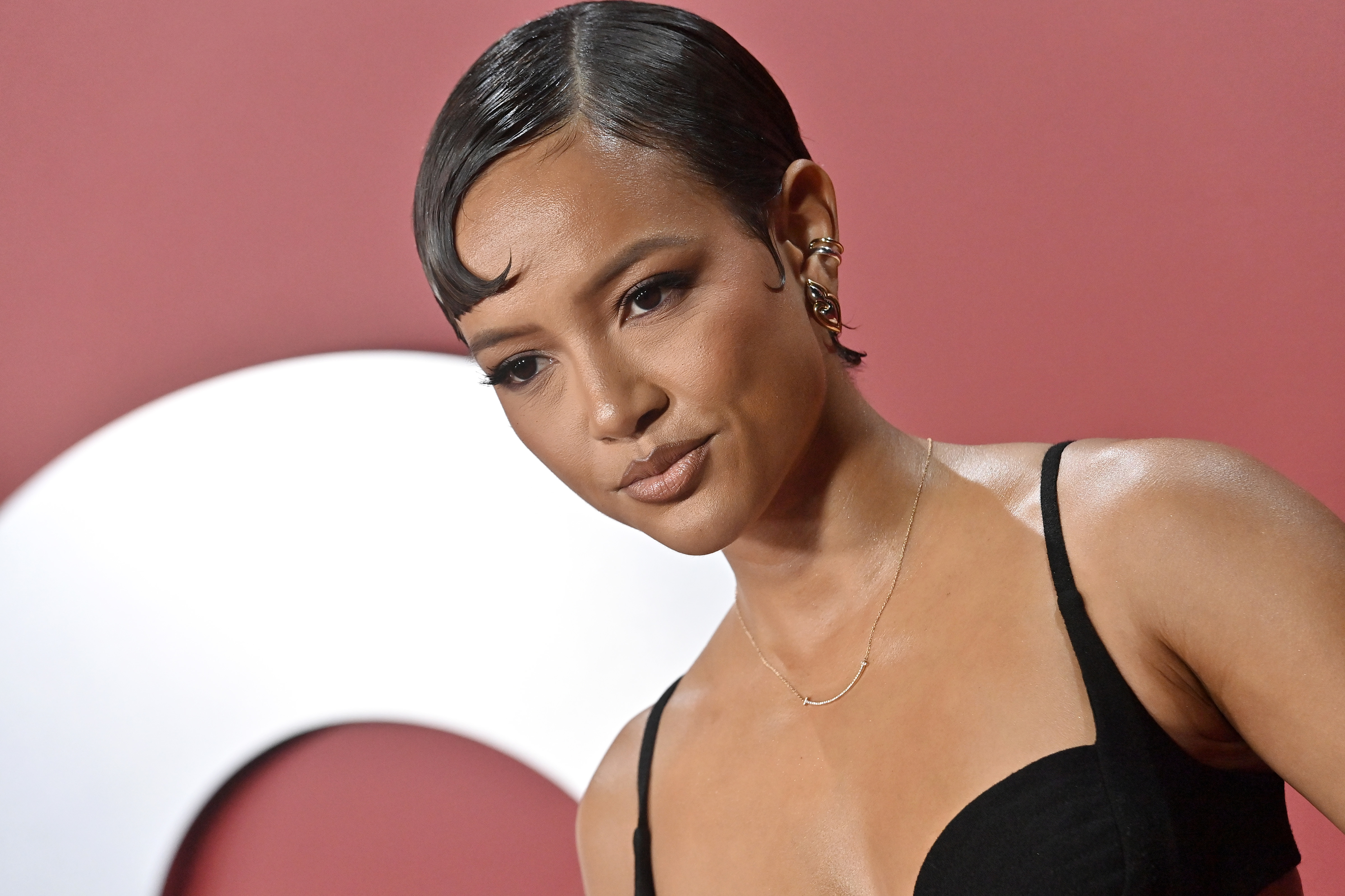 Karrueche Tran posing in a black sleeveless dress with her hair styled in a kicked back short haircut