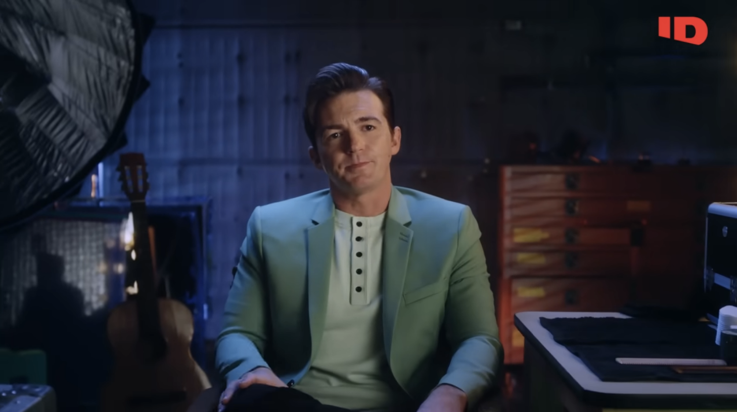 Closeup of Drake Bell sitting in a chair in a scene from Quiet on Set: The Dark Side of Kids TV