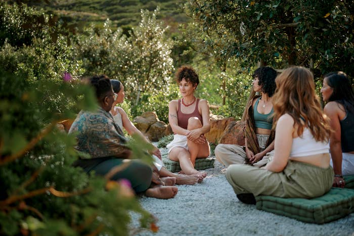 A group of women sitting in a circle outdoors on a large blanket