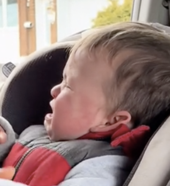 Toddler in a car seat, appearing to be mid-tantrum or crying