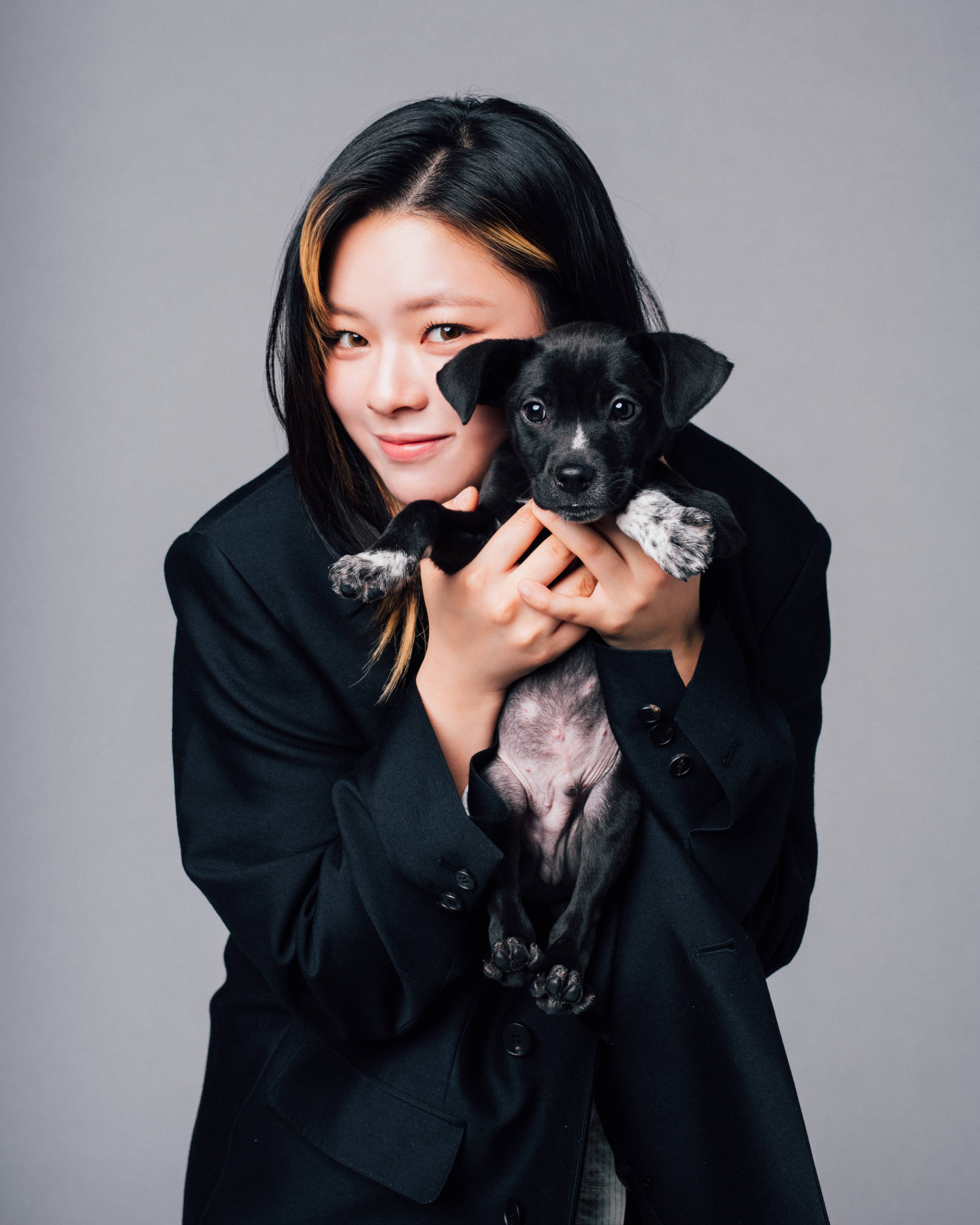 Woman in a blazer holding a small puppy