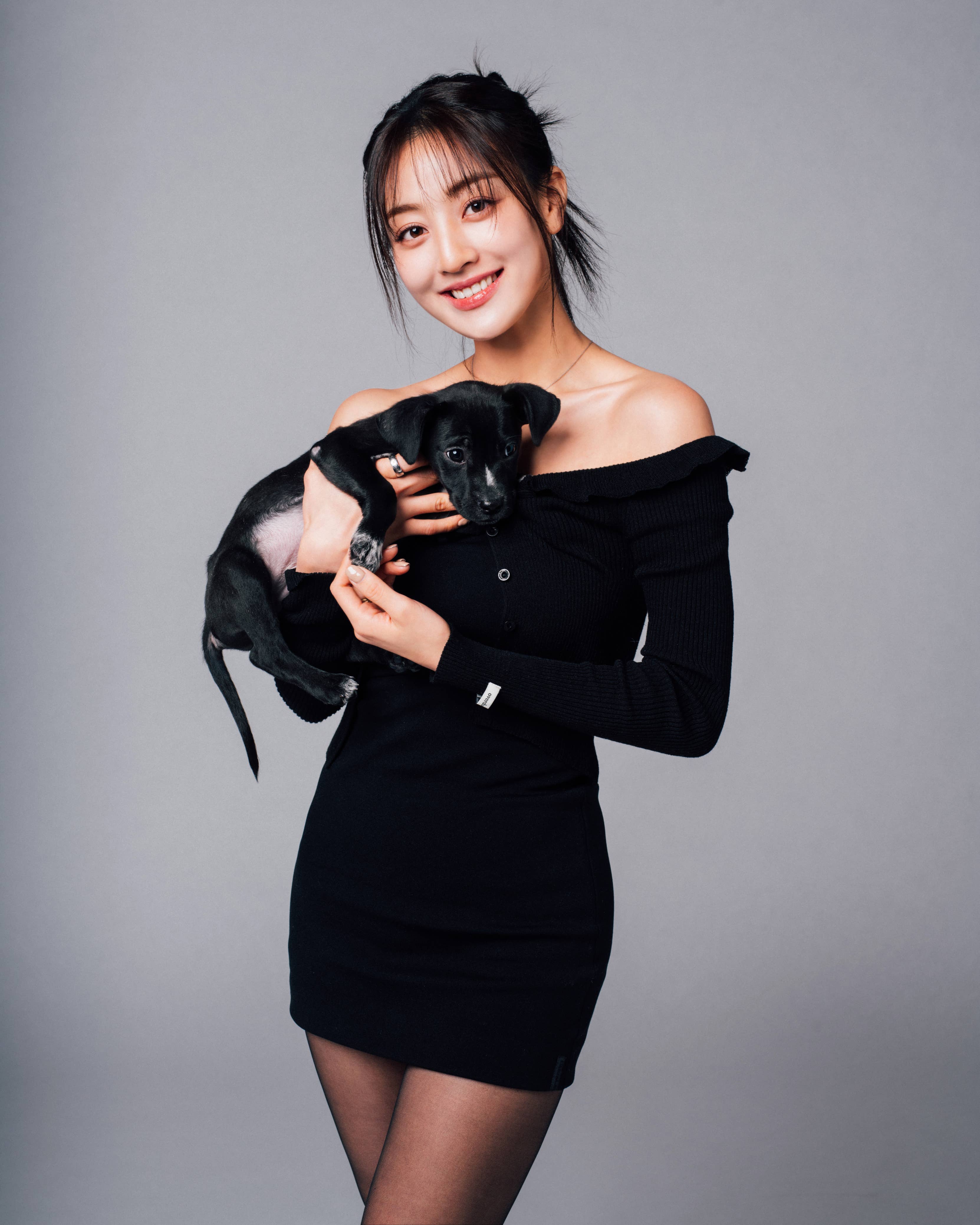 Woman in an off-shoulder dress holds a small dog