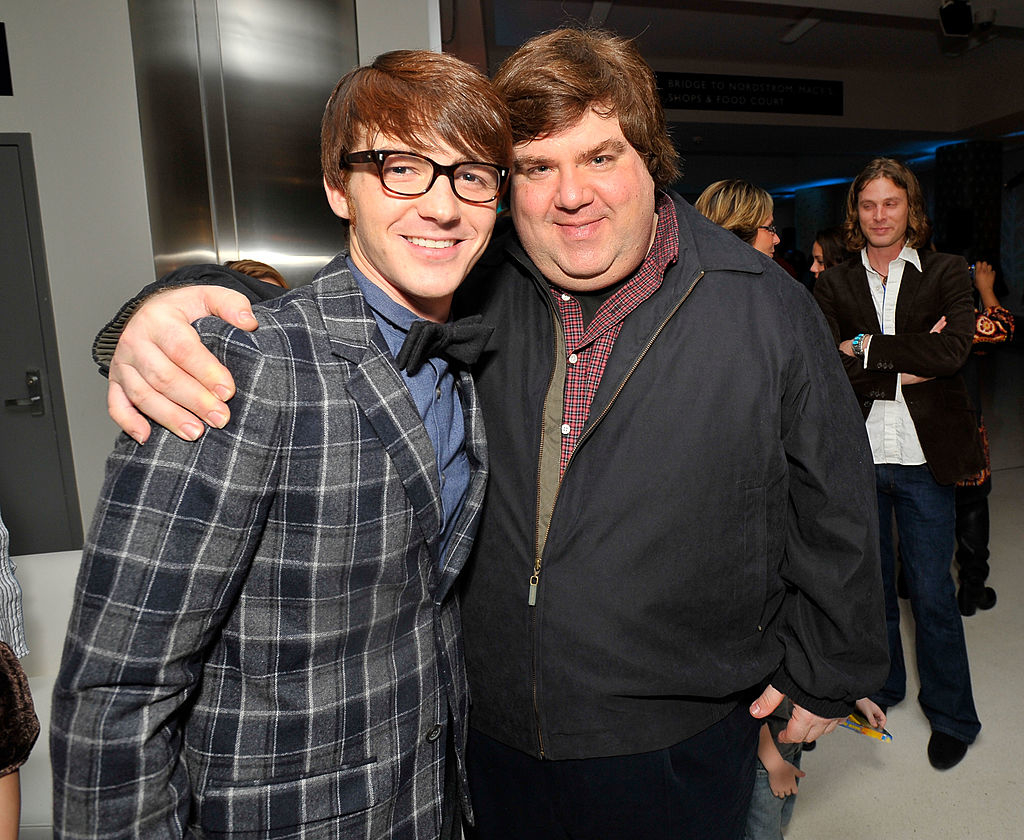 Dan Schneider stands with his arm around Drake Bell as they smile for a photo at an event