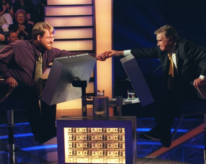 Two contestants engage in a handshake on a game show set