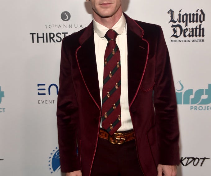 Drake Bell in a velvet suit with patterned tie, posing at an event