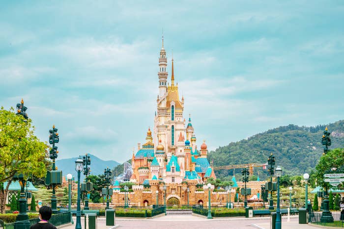 Fairytale castle at a theme park with surrounding greenery and a clear sky