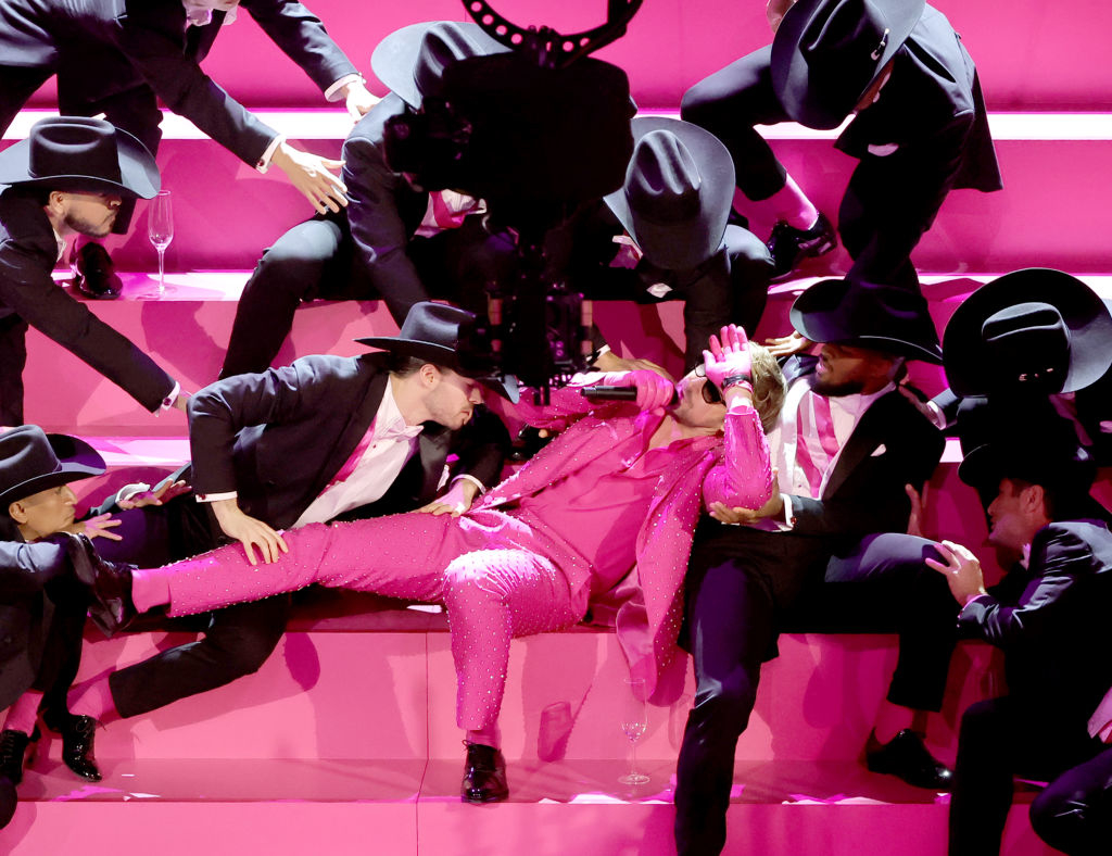 Ryan in pink outfit with dancers in suits and hats during a stage show