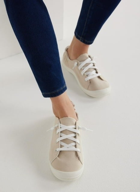 Person tying the laces of beige casual sneakers