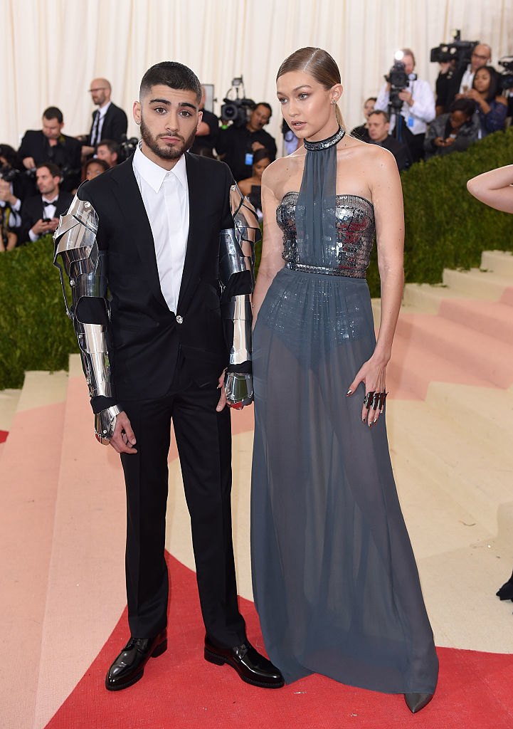 Zayn wears a tux with metal arms, and Gigi Hadid wears a sheer skirt over a metallic bodysuit