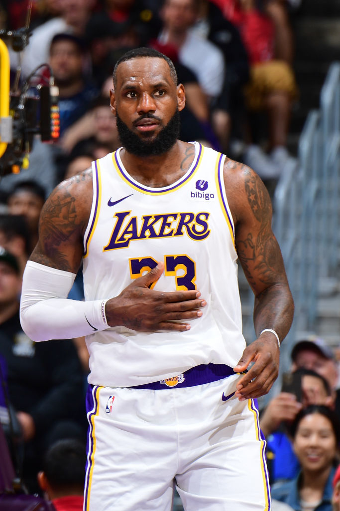 LeBron James in Lakers uniform on the basketball court, clapping hands, with spectators in the background