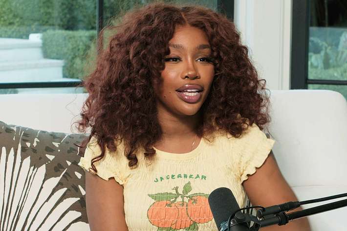 SZA sitting for an interview, wearing a stylish yoke-top with fruit design, casual-chic for the music-themed setting