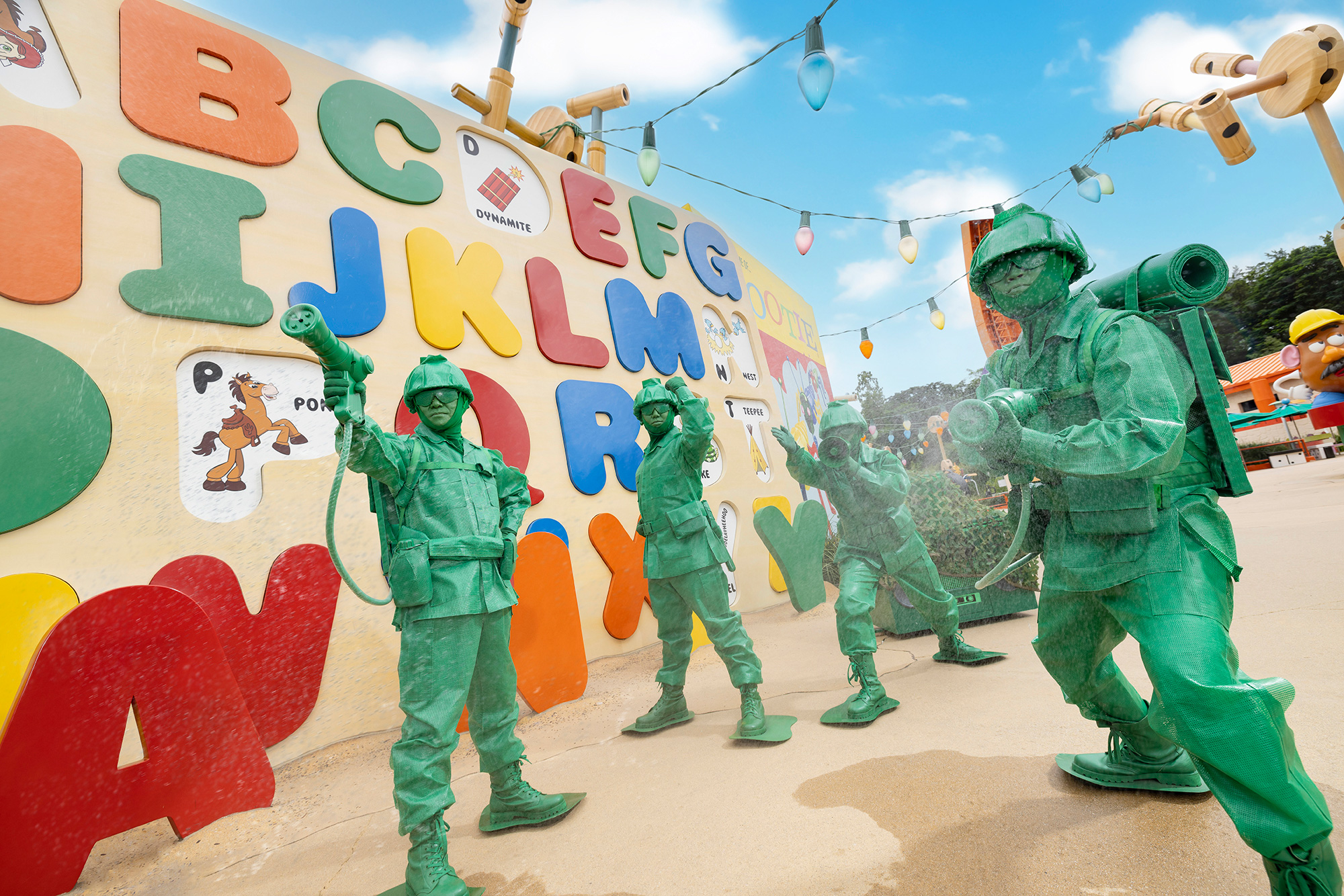 Three performers in green army men costumes from &#x27;Toy Story&#x27; pose at a themed park event