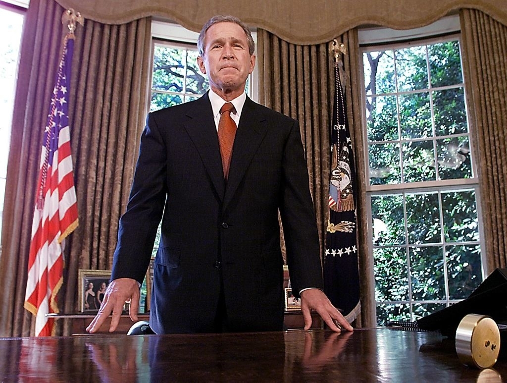 George W. Bush standing behind the Resolute desk in the Oval Office