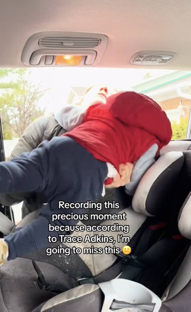 Child upside down in car seat seemingly singing, with humorous caption about missing these moments
