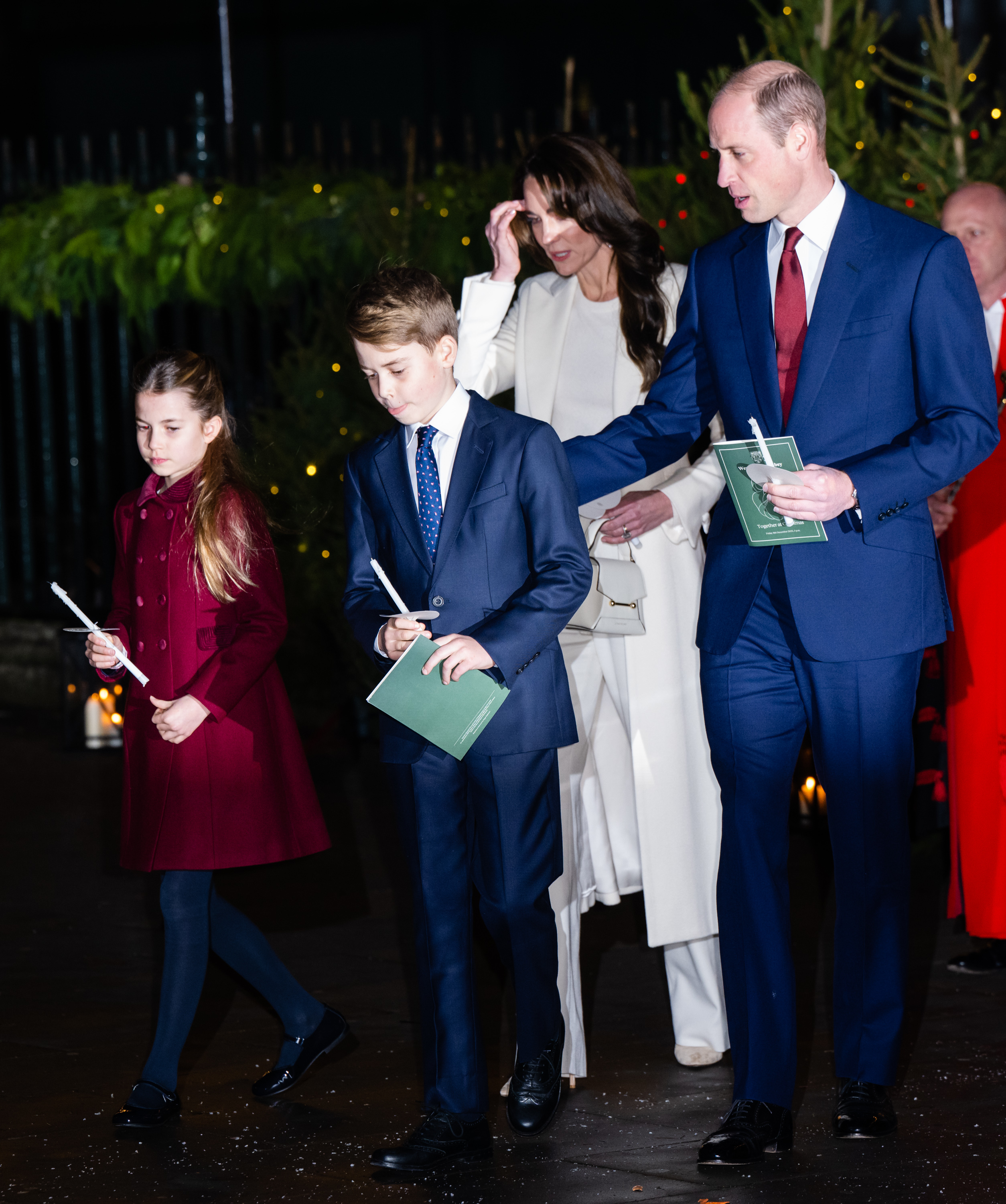 Prince William and family in formal attire at an evening event, holding programs
