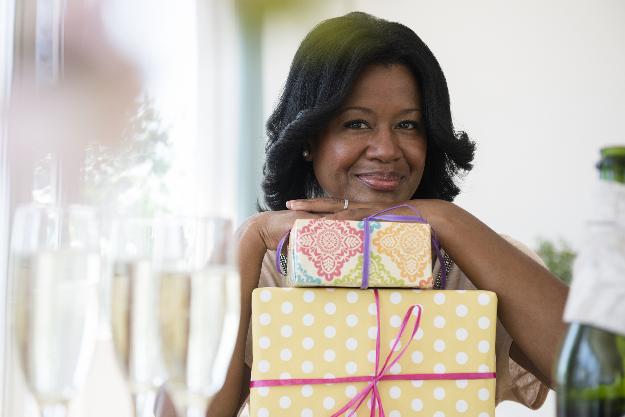 Woman smiling with a stack of gifts, expressing contentment