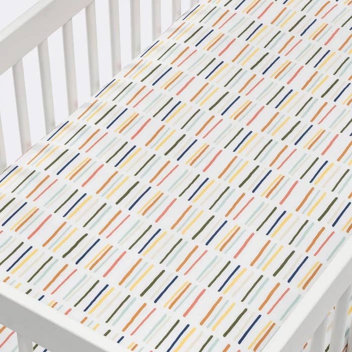Crib with multicolored striped mattress cover