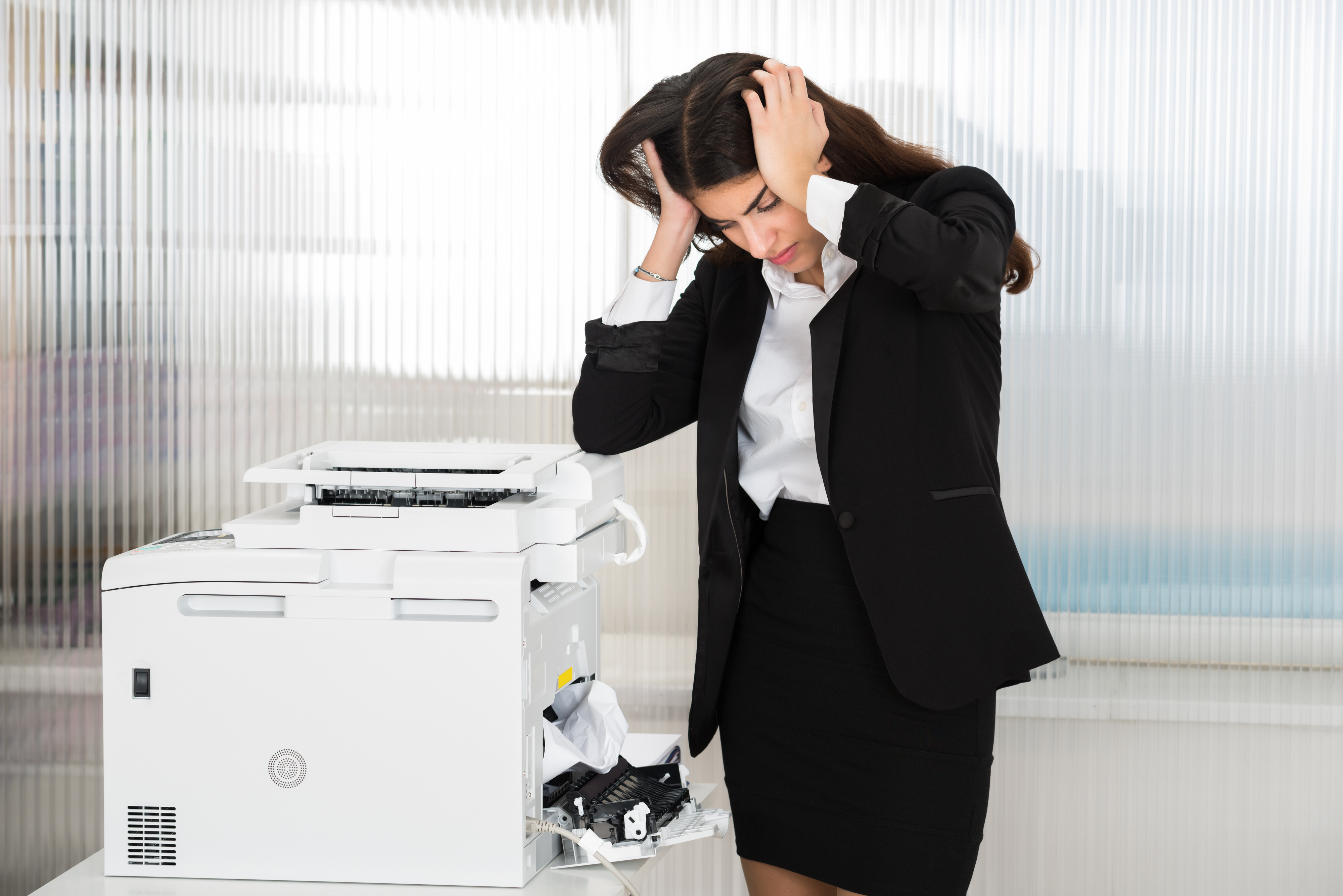 Woman appears frustrated with a jammed printer in an office setting
