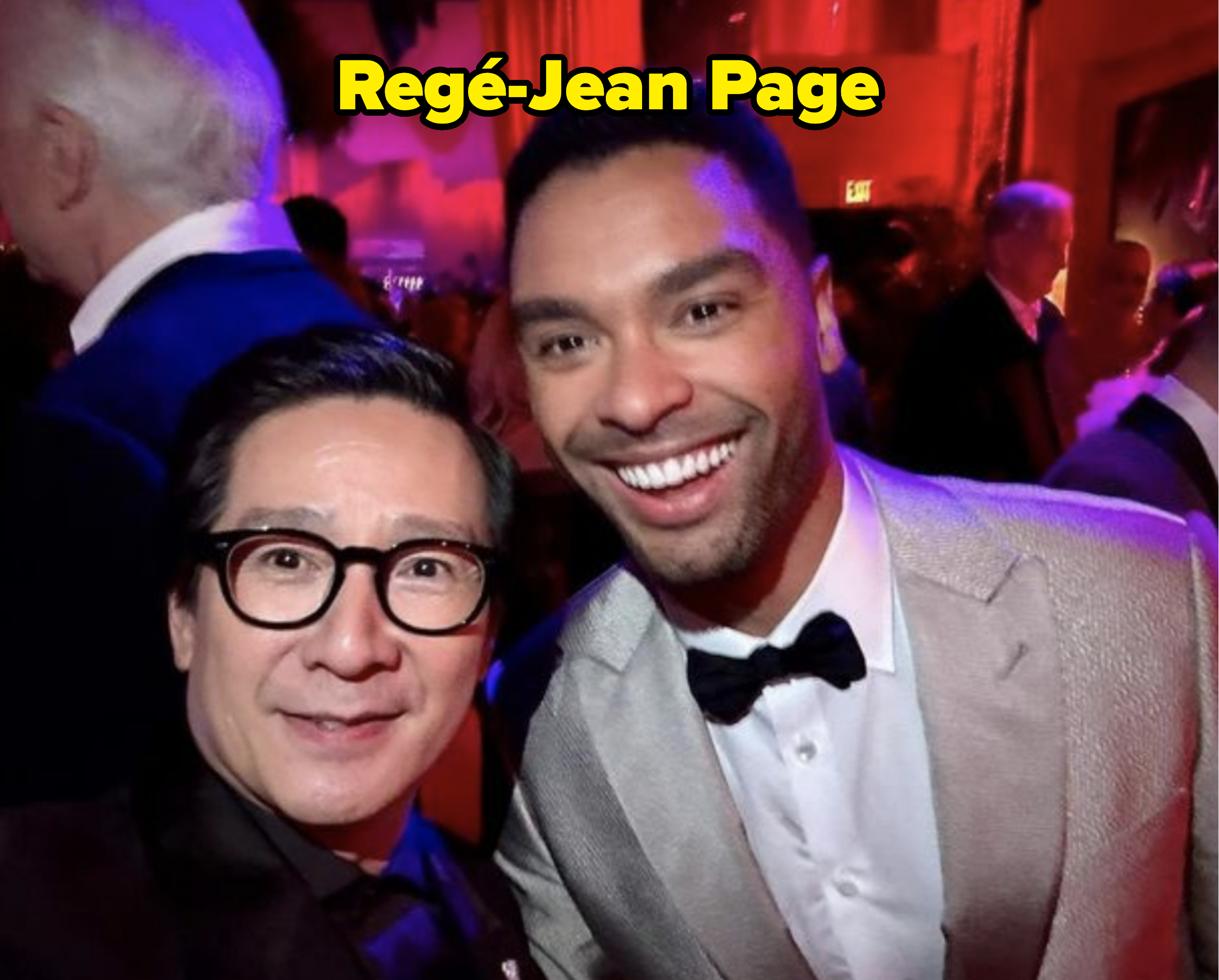 Two men smiling for a selfie at a formal event, one in a jacket and bow tie, the other in glasses