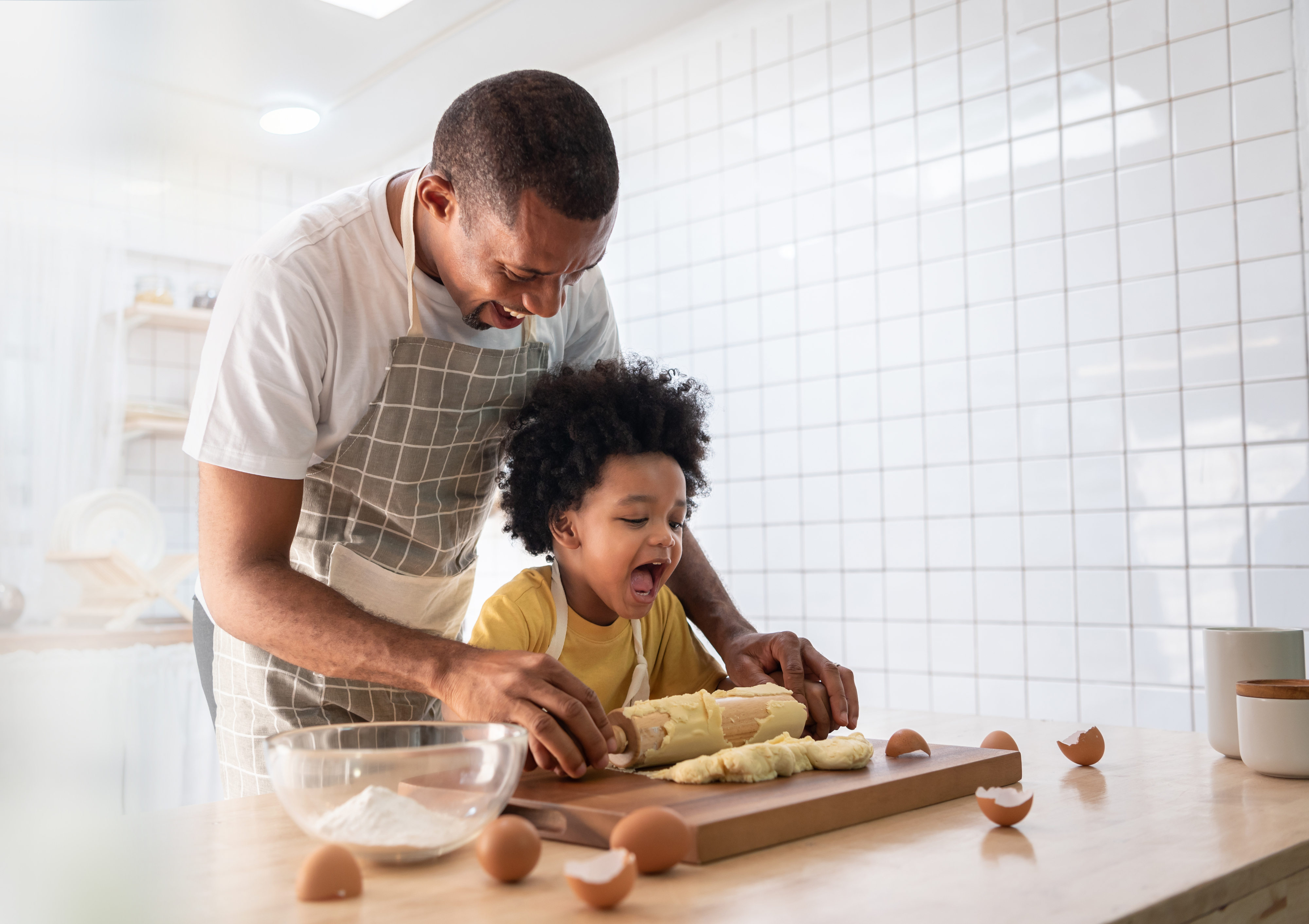 Man and child in aprons happily baking together in a kitchen