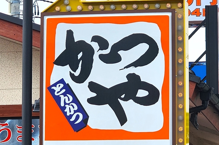 看板に大きな文字で「らーめん」の文字があり、下にPマークと矢印が表示されている。