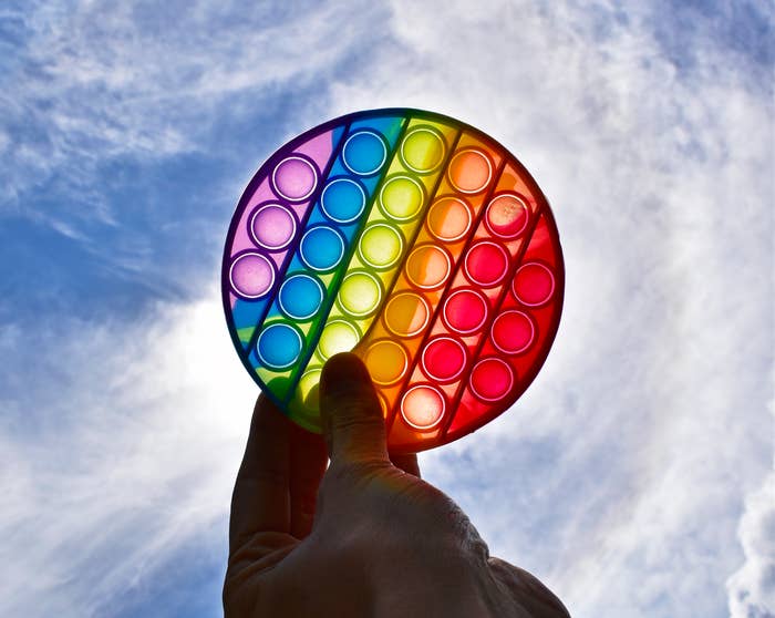 Person holding a pop-it toy against a cloudy sky