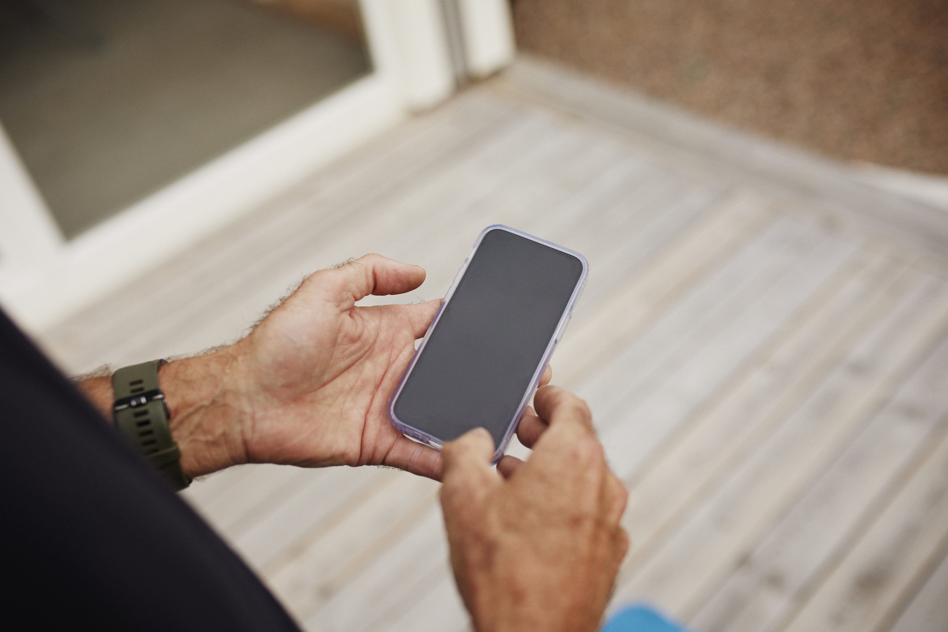 Person holding a smartphone with a blank screen, showcasing the device for advertising purposes