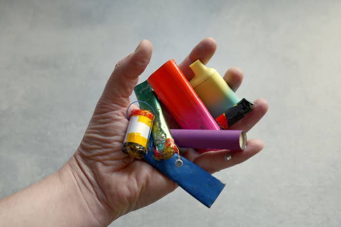 A hand holding a variety of used and discarded batteries