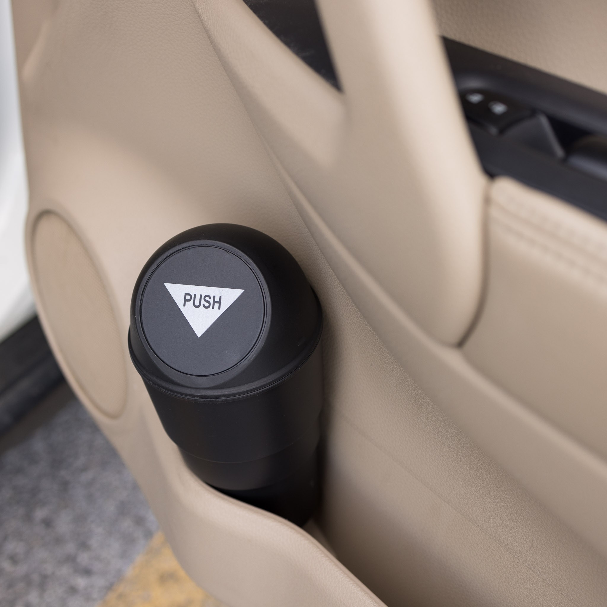 The mini trash can, with a round push lid, in a car&#x27;s side door cup holder