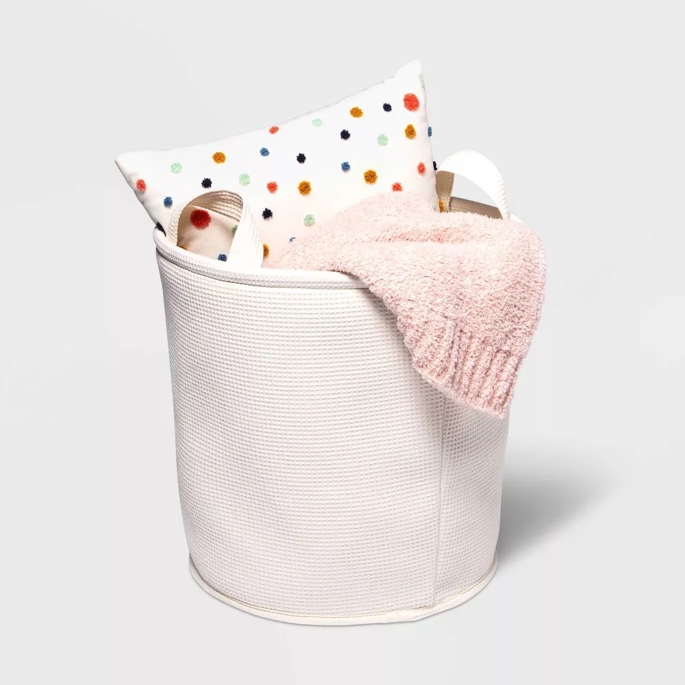 Textured laundry basket with towels and a polka dot cushion peeking out