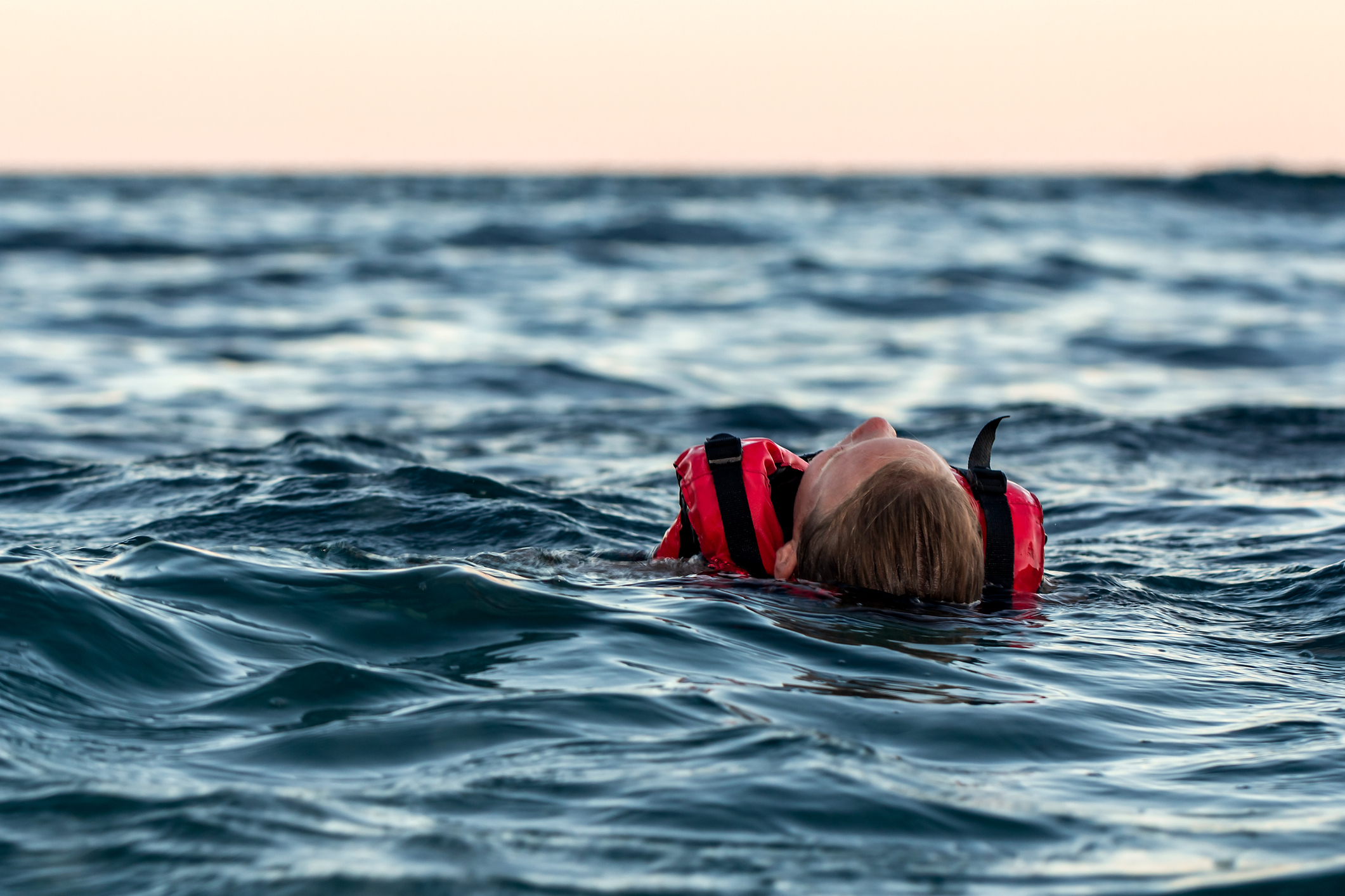Person with life jacket floating in the ocean, facing away from the camera