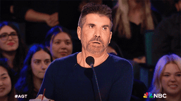 Simon Cowell with a surprised expression on &#x27;America&#x27;s Got Talent&#x27;, in front of a microphone and audience
