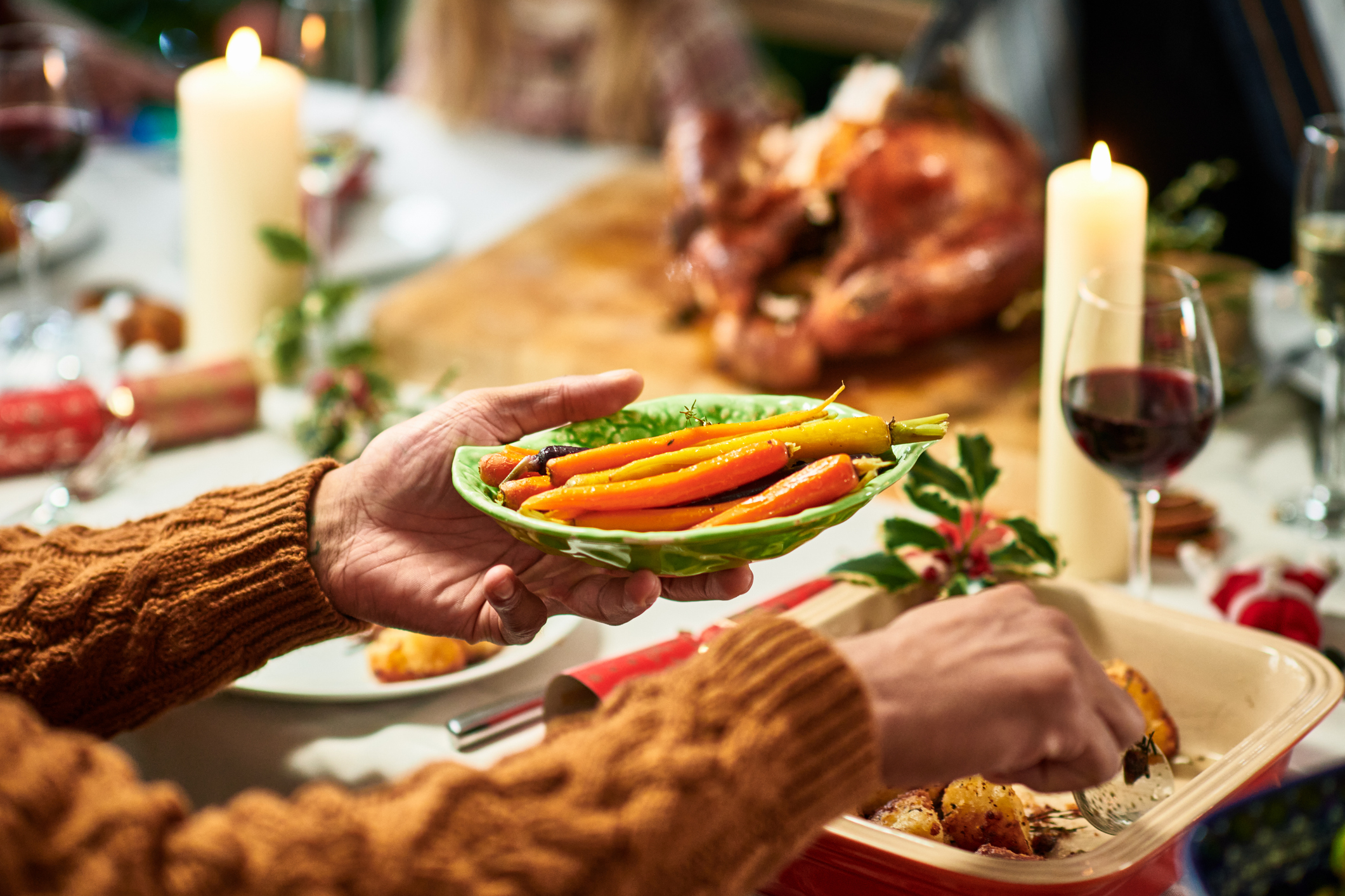 Person holding a plate of vegetables at a festive table with a turkey centerpiece
