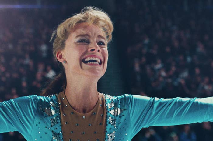 Woman portraying Tonya Harding in a blue costume figure skating with a joyful expression