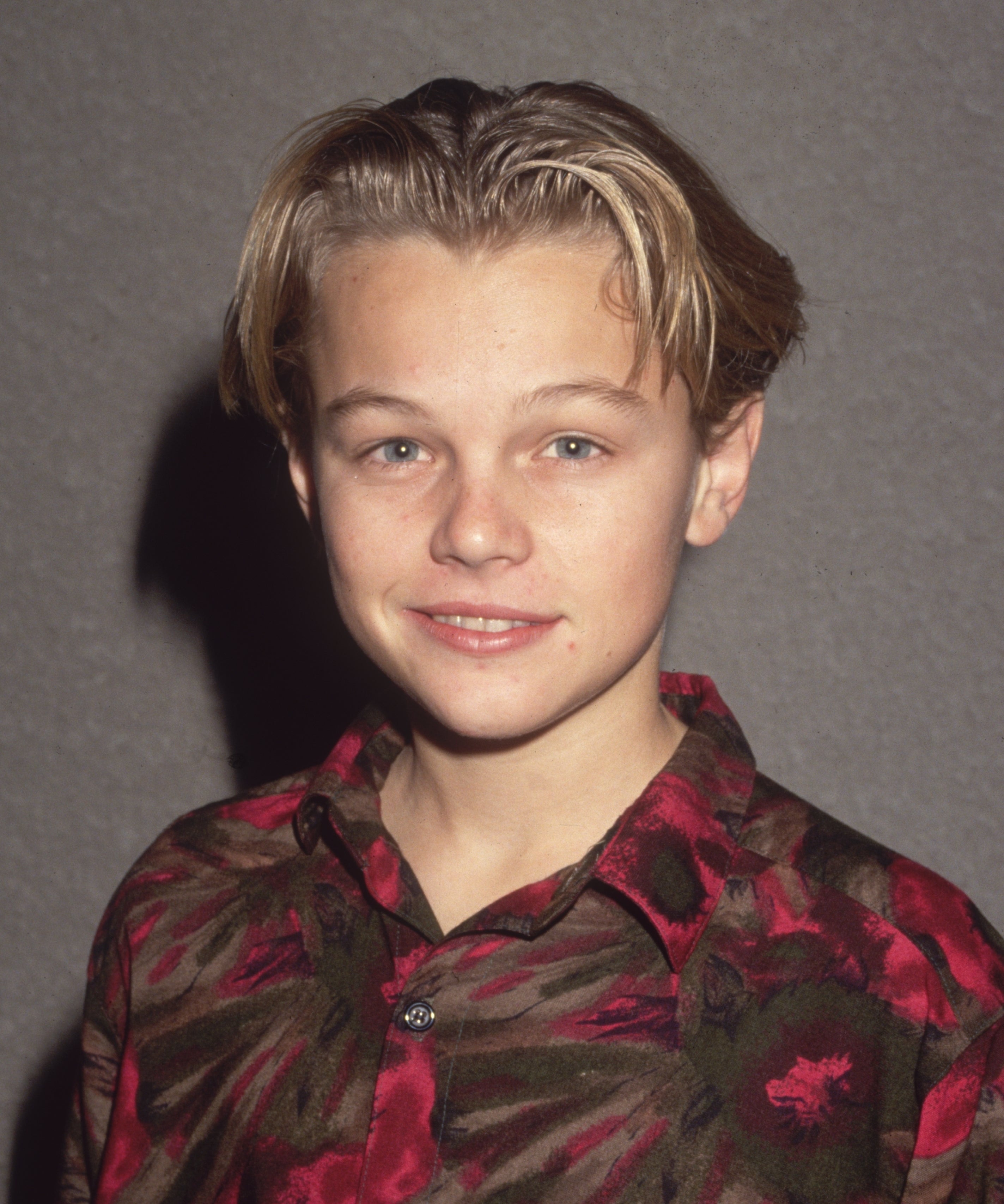 Young Leonardo DiCaprio smiling, wearing a floral patterned shirt