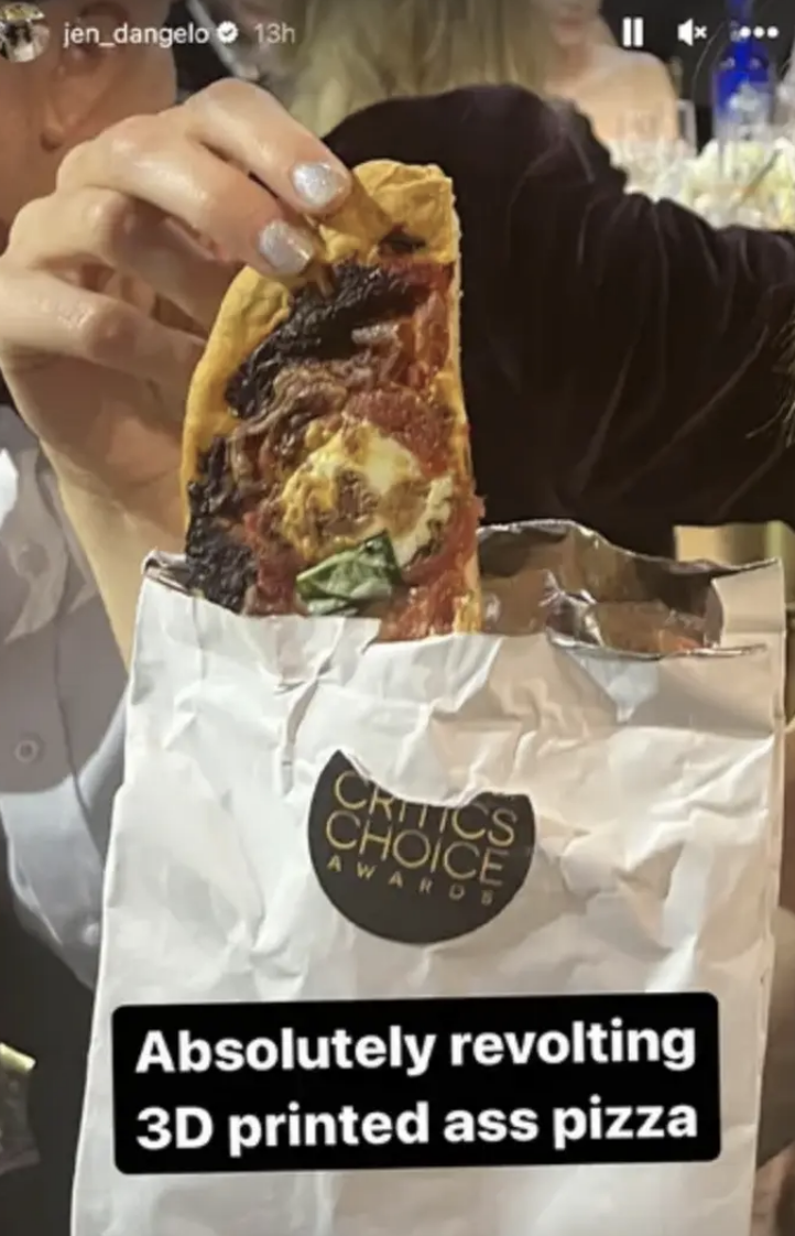 Person holding a slice of pizza with a Critics&#x27; Choice Award bag nearby. Text on image criticizes the pizza
