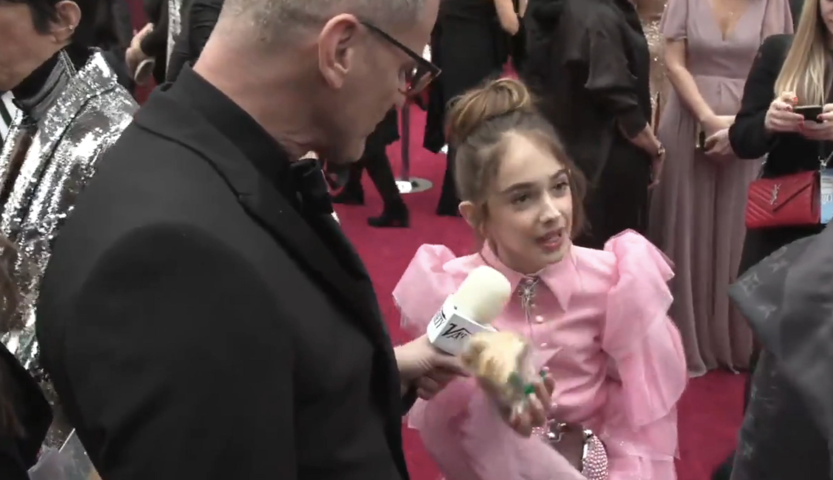 Julia in a ruffled outfit being interviewed by a reporter on the red carpet