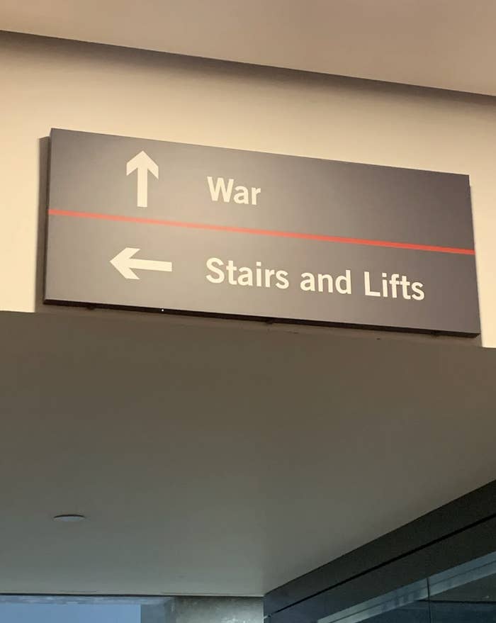Directional sign indicating &quot;War&quot; with an arrow pointing up, and &quot;Stairs and Lifts&quot; with an arrow to the left