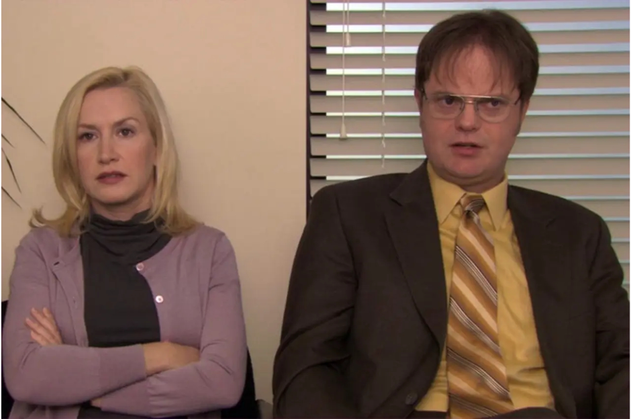 Two characters from &#x27;The Office&#x27; sitting side by side, the woman appears displeased with arms crossed