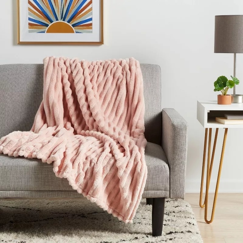 Plush pink blanket draped over a gray sofa