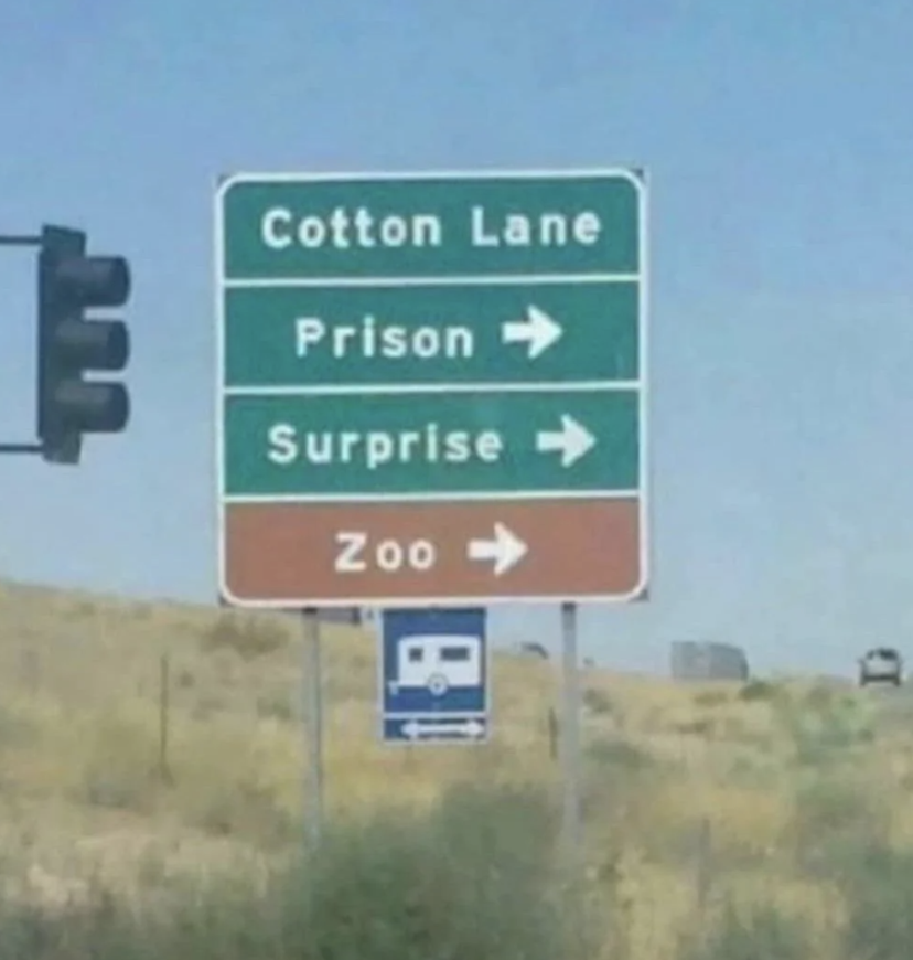 Road sign with directions: Cotton Lane, Prison to right, Surprise to right, Zoo straight ahead