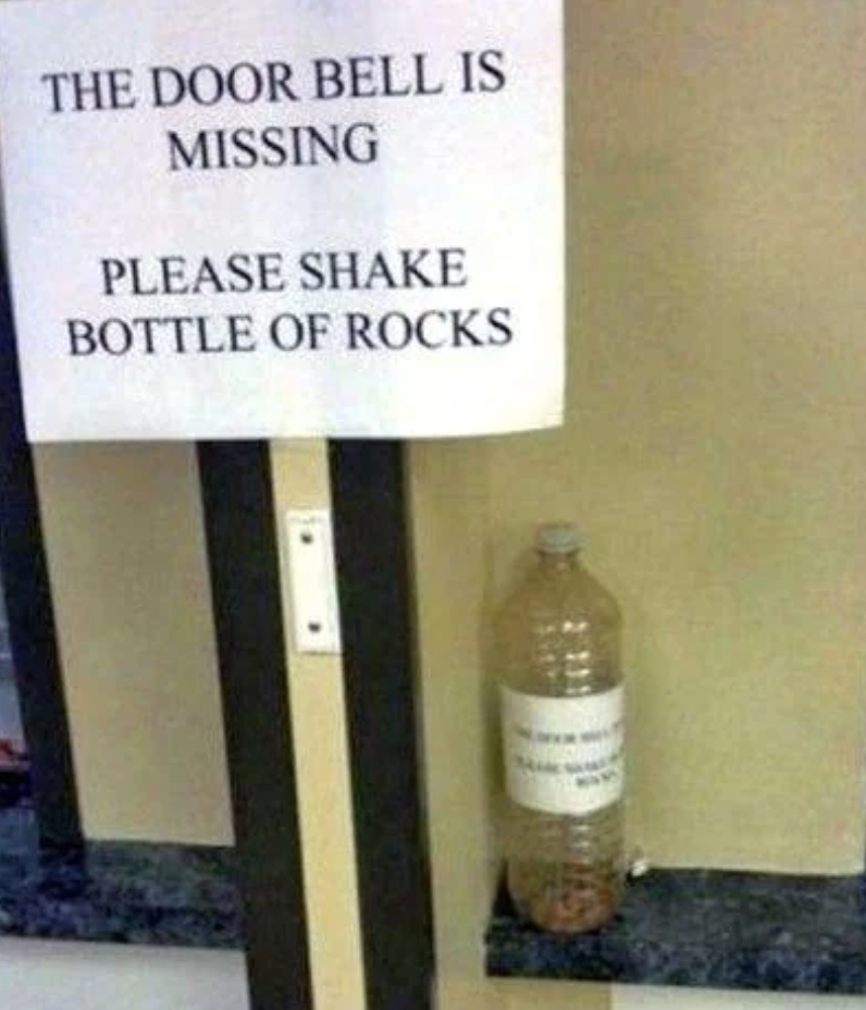 Sign reads &quot;THE DOOR BELL IS MISSING PLEASE SHAKE BOTTLE OF ROCKS&quot; next to a bottle filled with small stones
