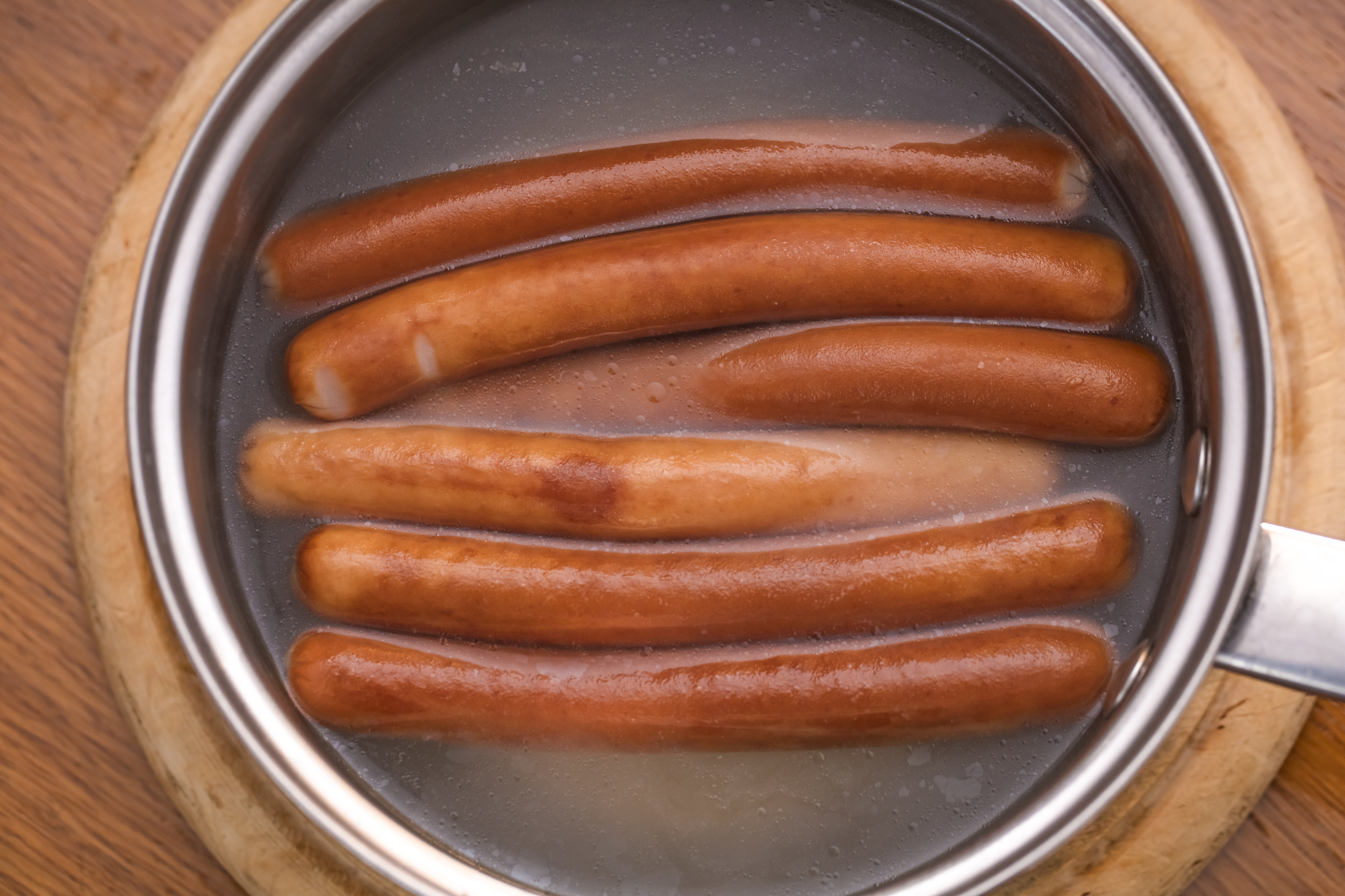 Hot dogs boiling in a pot on a stove
