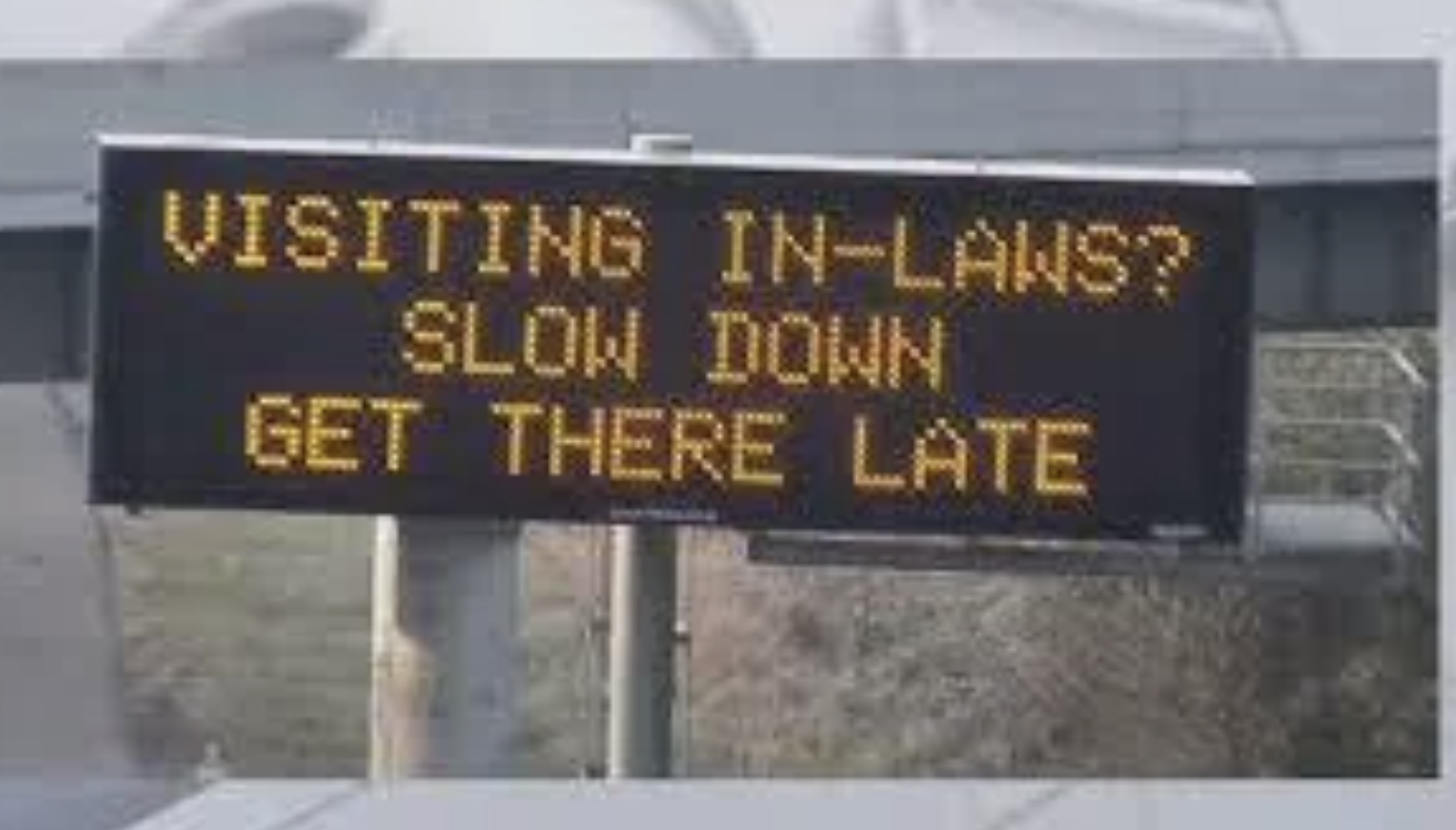 Electronic road sign with humorous message advising drivers to slow down if visiting in-laws, implying to delay arrival